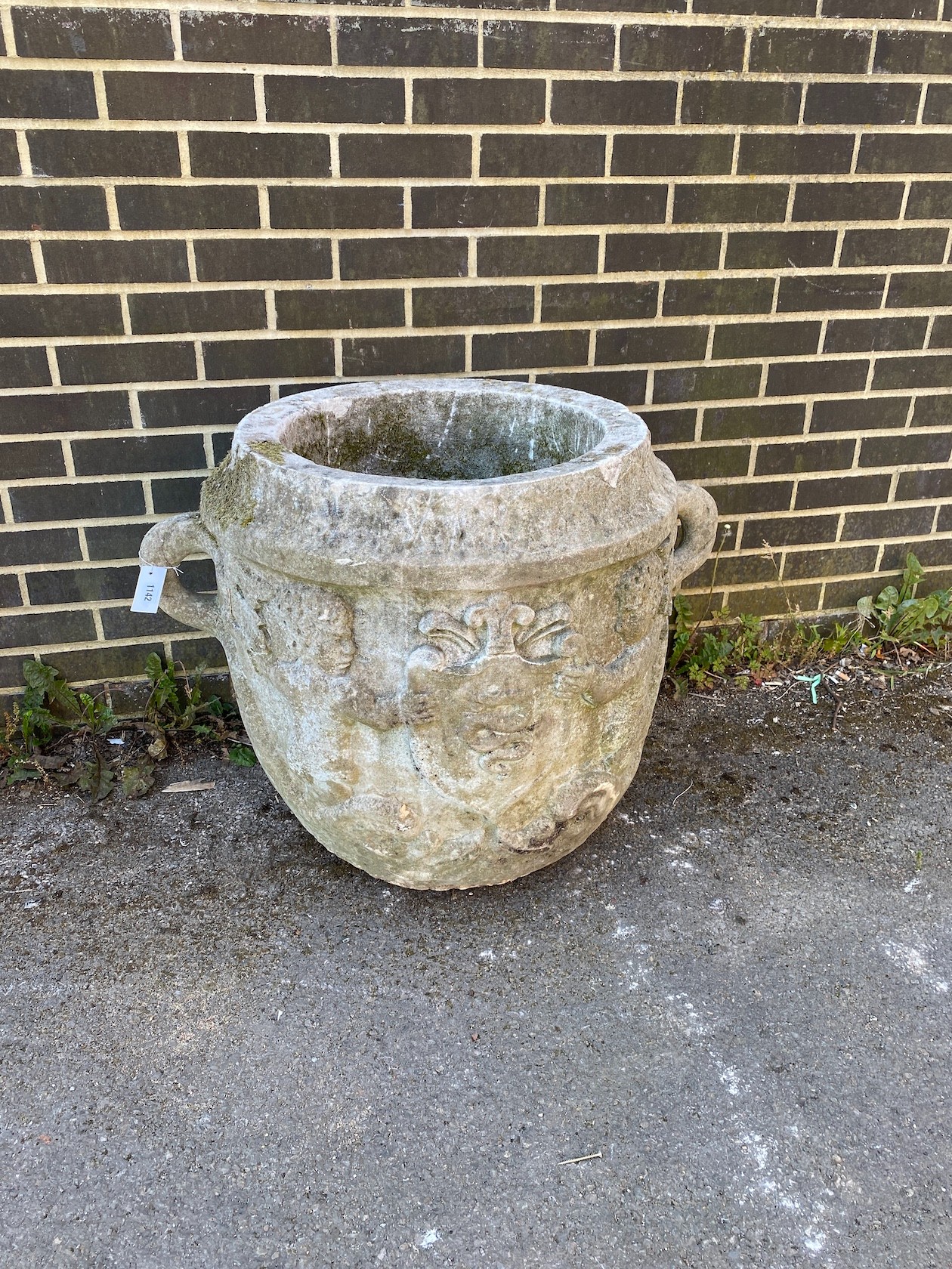 A large circular reconstituted stone garden planter with moulded serpent armorial, diameter 66cm, height 66cm